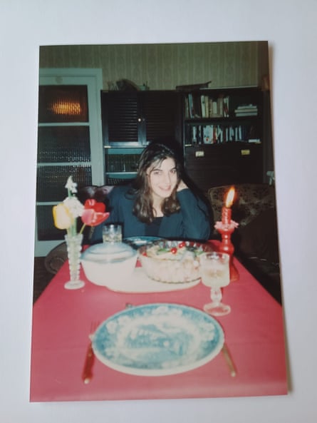 Paula aged 18 sat at a table in a living room, covered in a red table cloth, red candle and flowers
