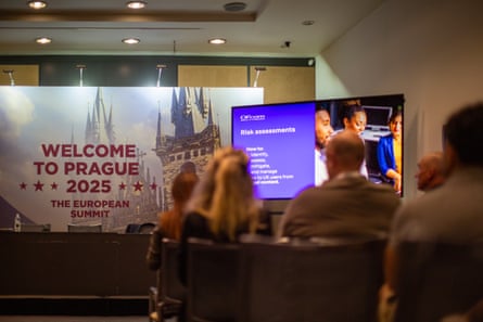 Seated delegates look towards a banner that reads ‘Welcome to Prague 2025’ and a screen introducing a presentation on risk assessment
