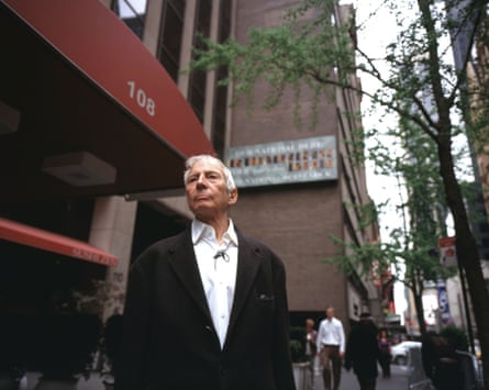 Robert Durst in The Jinx, standing outside a brown-bricked building with a red awning.