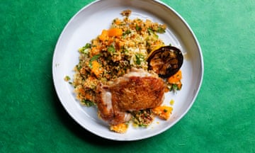 A round white plate with colourful bulgar wheat and a piece of grilled chicken on top