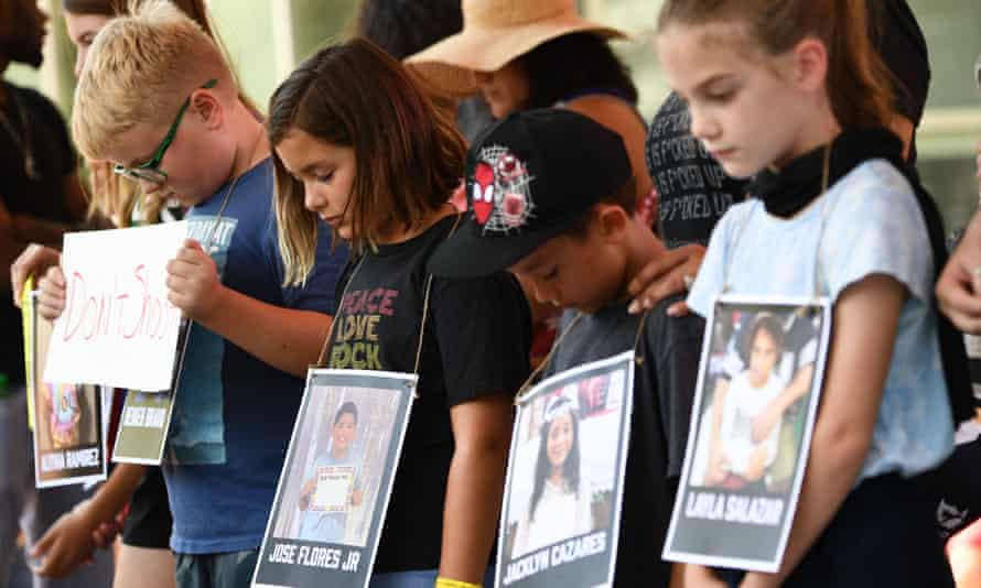 Children hold photos of victims of the Robb elementary school shooting, outside the NRA convention.