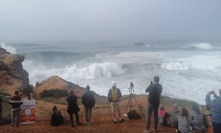 Os visitantes observam as ondas de perto do farol da Nazaré.