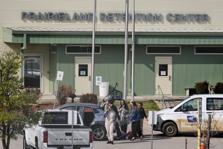a woman walks out of a detention center while waving