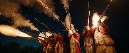 Soldiers in 18th-century redcoat uniforms firing guns