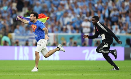A pitch invader wearing a shirt reading “Save Ukraine” holds a rainbow flag during the World Cup match between Portugal and Uruguay at Lusail Stadium last November.