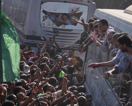 Freed prisoners lean out of bus windows to acknowledge crowds greeting them in the street.