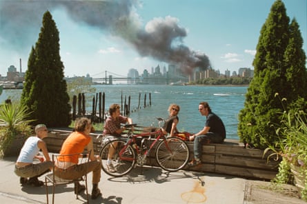 USA. Brooklyn, New York. September 11, 2001. Young people relax during their lunch break along the East River while a huge plume of smoke rises from Lower Manhattan after the attack on the World Trade Center.
