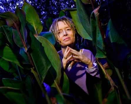 woman wearing purple sweater in between plants outside