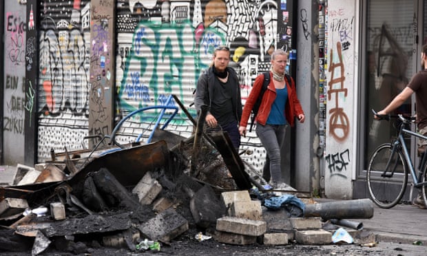 Residents in the Schanzenviertel district of Hamburg pass by a pile of burned debris following looting and rioting by G20 protesters.