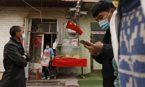 A vendor selling naan bread waits for customers on a street under surveillance cameras in Shule county, Xinjiang