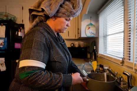 Woman with a towel on her head filling up a pot at the tap