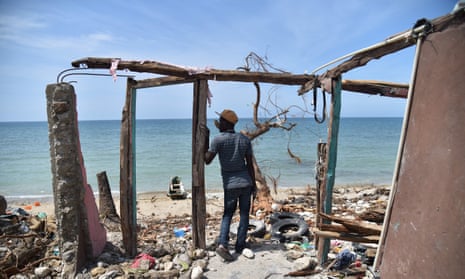 A man stands next to a destroyed house in Les Cayes, Haiti following Hurricane Matthew.