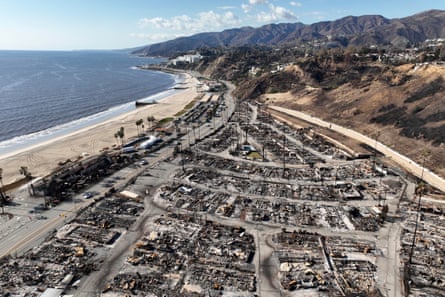 Aerial view of burned neighborhood between ocean and hills.