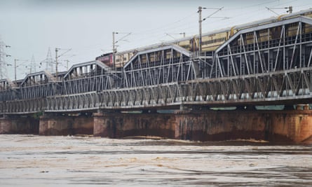 The train drives over an old bridge made of rusting metal girders