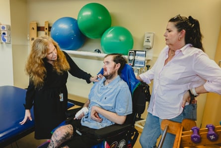 Two women talking, a man sits in a wheelchair between them