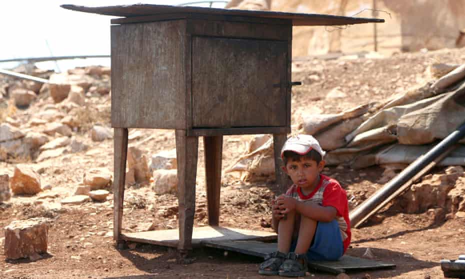 A Palestinian boy sits in the shade while his family search for their belongings after their shack near Ramallah was demolished by the Israeli army. More than 11,000 demolition orders are still outstanding.