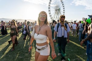 A woman wearing sunglasses smiling for the camera, with a ferris wheel in the background
