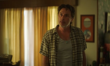 A middle-aged man standing in a living room with the curtains closed