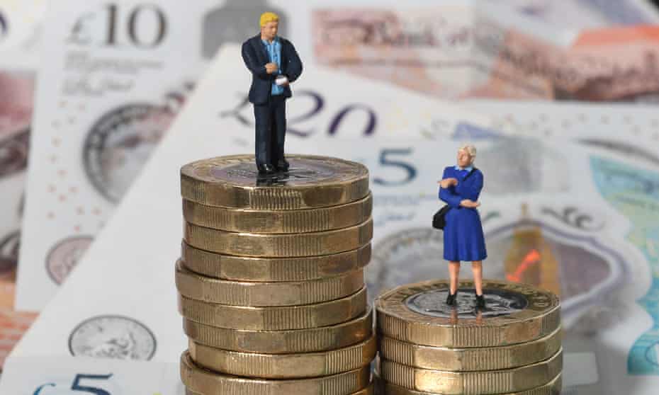 Models of a man and woman stand on a pile of coins and bank notes