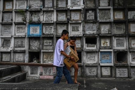 Relatives of a victim of the government’s drug war carry a box containing the remains after they were exhumed at Bagbag cemetery in Novaliches, Metro Manila, in June 2022