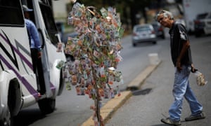 A man looks at Venezuelan bolÃvar notes hung to resemble a tree,in Caracas, Venezuela, on 6 March.