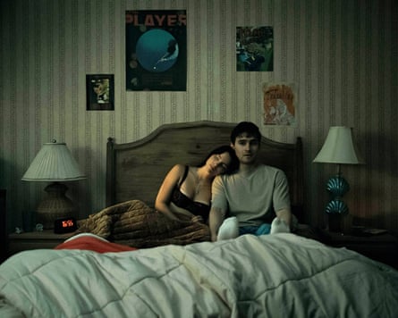 A couple sitting in bed, the woman resting her head on the man's shoulder, in a scene from Obsession