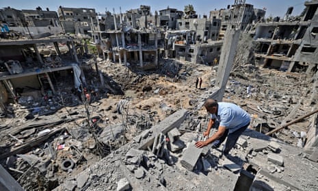 A Palestinian man standing in rubble assessing the damage caused by Israeli air strikes