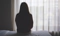 Rear view image of a woman sitting alone on a bed in bedroom