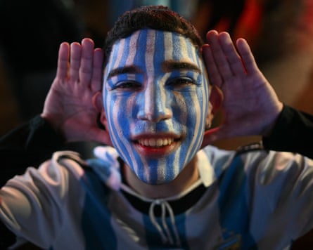 An Argentina supporter with blue-and-white face paint gestures as fans celebrate Argentina’s victory over England following the 2026 FIFA World Cup semi-final football match near the Obelisk in Buenos Aires