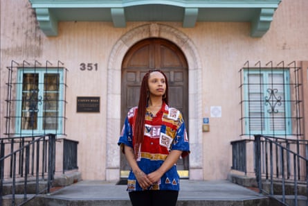 A woman stands in front of a light-colored building