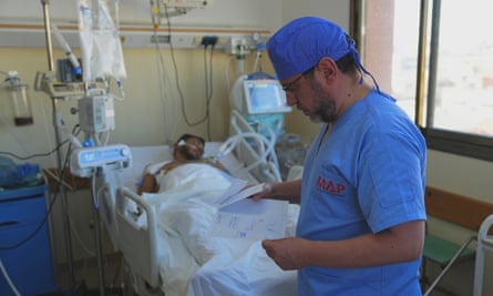 A doctor stands by a hospital bed with a patient