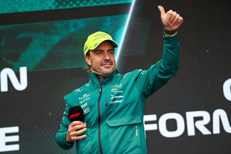 Fernando Alonso smiles and gives a thumbs-up at a fan forum before the first free practice session for the F1 Hungarian Grand Prix