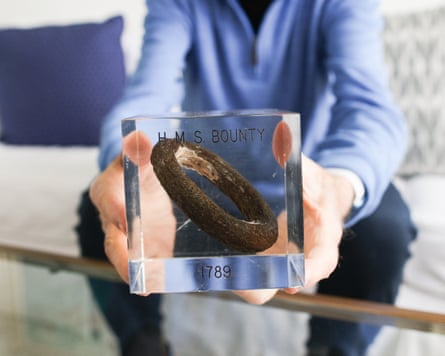 A man holds a rusted ring of metal preserved in resin towards the camera