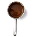 A metal saucepan filled with dark caramel