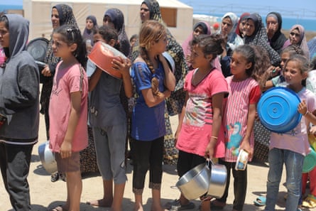 Children in Gaza wait in line holding basins and pits and pans