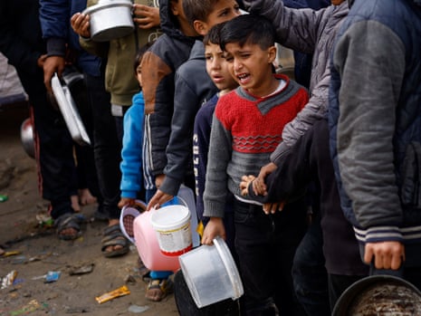 Los palestinos esperan recibir alimentos en medio de la escasez de alimentos en Rafah.