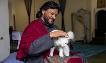 Imam Muhsin sorrindo e acariciando um gato branco fofo