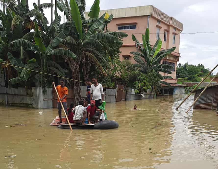 A patient is escorted to hospital on a makeshift raft constructed out of wood and tire inner tubes.