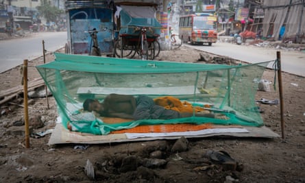 Bangladeshi worker sleeps under a mosquito net to avoid infection