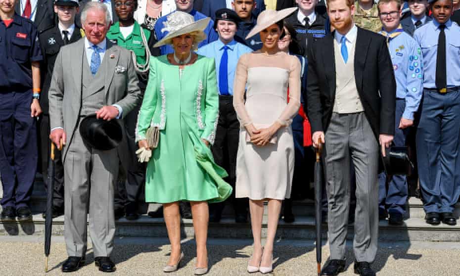 Prince Charles, Camilla, Duchess of Cornwall, Meghan, Duchess of Sussex, and Prince Harry, standing at the front of a crowd at Buckingham Palace