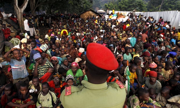 A Tanzanian policeman watches over Burundian refugees gathered on the shores of Lake Tanganyika in the Kigoma region.