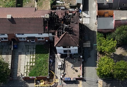 Aerial view of a white end of terrace house with its roof burnt out.