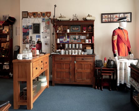 A museum room featuring two dresser cabinets full of showpieces, and a mannequin in a red uniform jacket and black cap