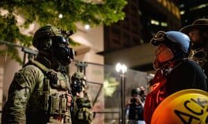 A federal agent faces off with a protester outside Portland’s downtown courthouse.