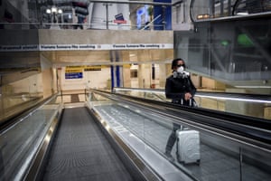 A woman wears a mask as she stands on an escalator inside Central train station, in Milan, Sunday