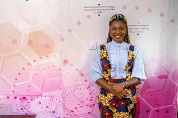 A woman smiles for the camera, leaning against a backdrop with inspirational quotes