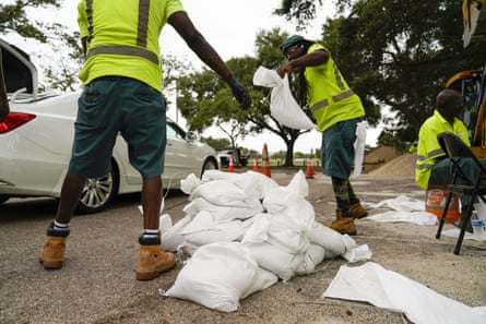 City employees load sandbags into people’s cars as they pull up to a station at Northwest Park, in preparation for Hurricane Ian.