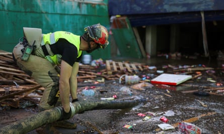 An emergency worker holding a pipe removing water from the shopping centre car park.