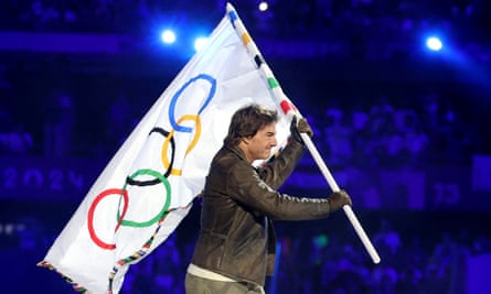 Tom Cruise holds the Olympic flag during the closing ceremony.