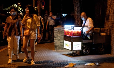 A street vendor selling sweets waits for customers along a street in Beijing on 11 June